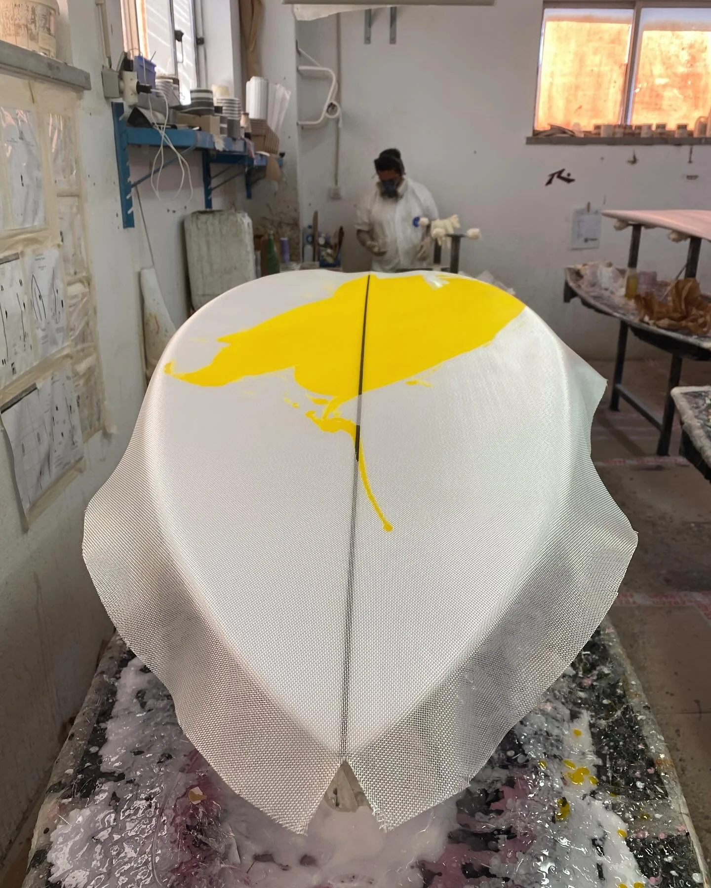 Wet layup in progress: cloth draped over a board, yellow resin tint working through the weave