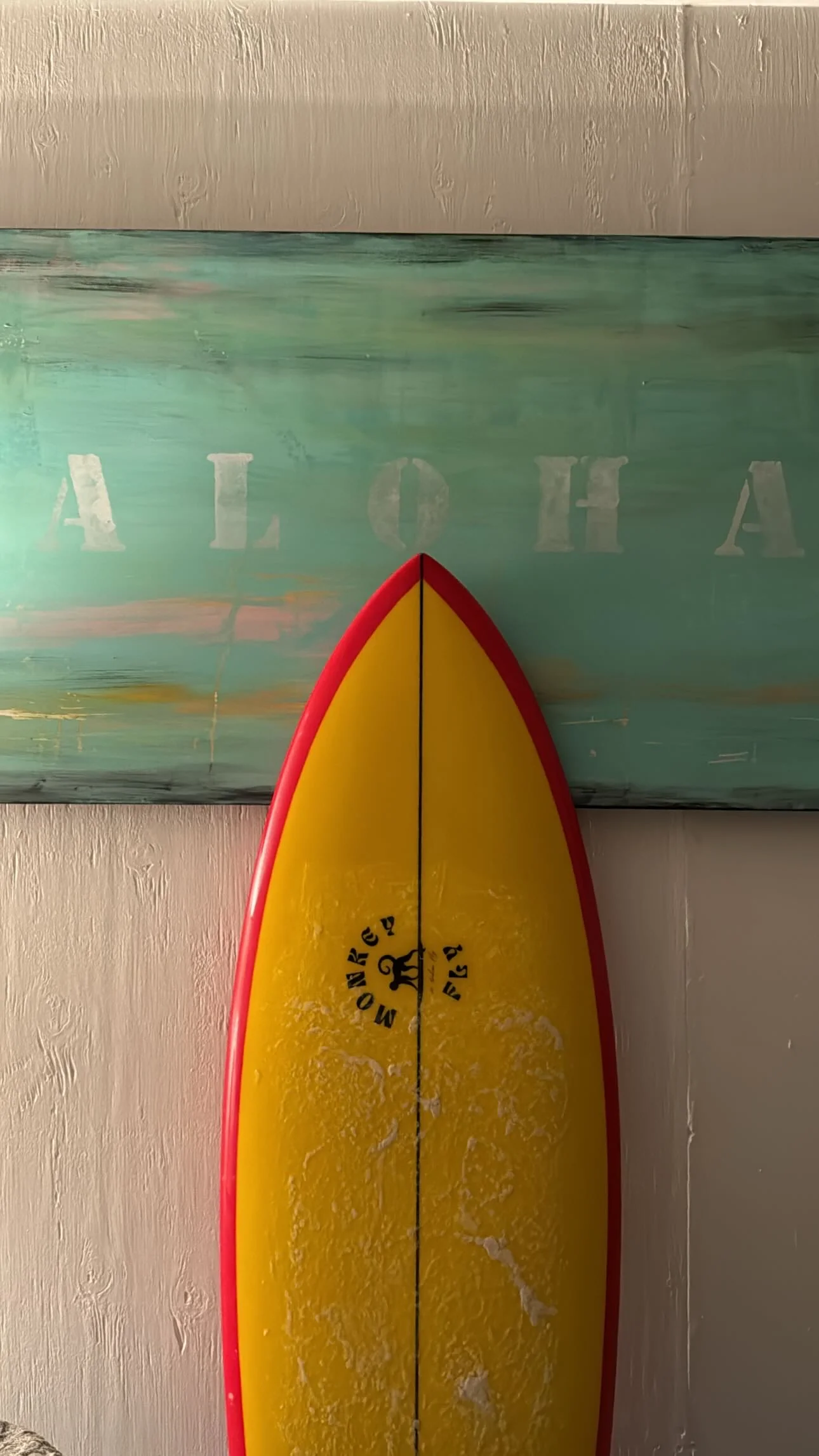 Yellow twin fish with red rails leaning against a painted wall sign